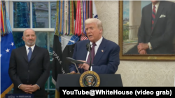 美国总统唐纳德·特朗普在白宫椭圆形办公室与苹果首席执行官蒂姆·库克共同出席一场活动时，手上拿了一个B-2轰炸机模型。(2025年8月6日)