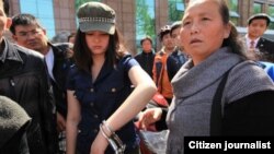 汪姓女青年在手铐打开一只后戴着手铐跟围观路人在一起。(网络图片)