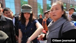 武汉市一位汪姓女青年在手铐打开一只后戴着手铐跟围观路人在一起。她被誉为学雷锋的女孩,2013年为救人助人,向执勤民警求助无果后,因用脚踢警车来宣泄愤怒而遭警察以手铐铐住(网络图片)