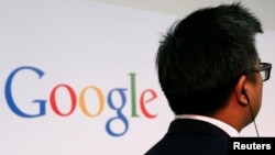 一位男士站在谷歌的标牌前方。(2013年11月4日)