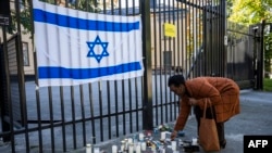 2023年10月9日,巴勒斯坦激进组织哈马斯对以色列发动突然袭击后,一名妇女在以色列驻瑞典斯德哥尔摩大使馆外放置蜡烛以表示声援和支持。(法新社照片)