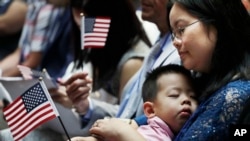 资料照片:一名来自中国的移民抱着儿子参加在纽约公共图书馆举行的入籍仪式。(2018年7月3日)