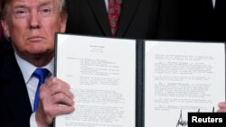 Tổng thống Donald Trump giơ bản thông tri loan báo kế hoạch đánh thuế lên tài sản trí tuệ và các sản phẩm công nghệ cao của Trung Quốc, tại Nhà Trắng ở Washington, ngày 22 tháng 3, 2018.