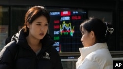 资料照:北京街头两名女子站在显示中国股市走势的展示板前。(2024年11月6日)