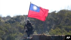 资料照:一名台湾士兵手举台湾旗帜参加新竹举行的军演模拟反击中国军队攻台。(2021年1月19日)