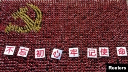 中国浙江省金华市的中共党员手举“不忘初心牢记使命”的标语牌组成中国党旗图案的阵仗。(2019年6月28日)