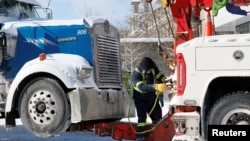 在渥太华,一位男士准备把一辆参加抗议疫苗强制令活动的卡车拖走。(2022年2月18日)