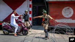 印度准军事士兵在铁丝网路检查站查问一名骑摩托车的人。(2017年7月7日)