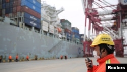 中国山东青岛港的一名戴着口罩的工人在集装箱码头工作。(2020年2月4日)