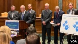 “关税伤害美国心脏地带”发言人、前国会议员查尔斯·布斯塔尼在参议院德克森办公大楼讲话,站在他身后(从右至左)的是四名资深联邦参议员。(2019年2月6日)