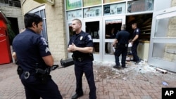 2016年9月22日,美国北卡夏洛特市,警察站在一个被抗议人群砸毁的店铺前面。