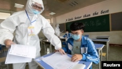 中国河北邯郸一所高中在举行模拟高考时身穿防护服的监考老师在发试卷。(2020年7月1日)