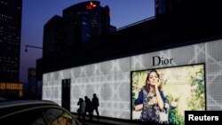 资料照片:北京市民走过一家商场外的迪奥广告牌。(2016年11月30日)