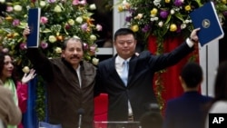 资料图片:在这种2013年6月14日的资料照片中,尼加拉瓜总统丹尼尔·奥尔特加和中国商人王靖在首都马那瓜的Casa de los Pueblos举起一份价值数十亿美元的运河建设特许权协议。2014年1月8日,获得建设和运营横跨尼加拉瓜的跨洋运河特许权的中国公司表示,该项目将为2.5万名尼加拉瓜人和2.5万名外国人创造就业机会。