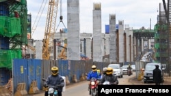 资料照片:驾车者在蒙巴萨公路上行驶,旁边是正在施工的内罗毕高速公路,由中国路桥公司承建。(2021年7月12日)