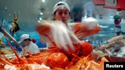 资料照:澳大利亚悉尼海鲜市场的一名商贩在展示他烹饪的龙虾。