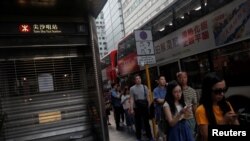 10月5日,人们在一关闭的香港地铁站外等公共汽车。(路透社)