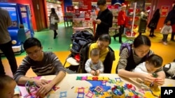 资料照片：在北京哈姆雷斯(Hamleys)玩具店内，家长和孩子们在活动站一起玩耍。(2017年12月23日)