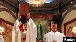 资料照: 北京天主教堂里的一名神职人员在做圣诞弥撒时高举中文版的圣经。(2007年12月24日)
