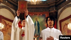 资料照: 北京天主教堂里的一名神职人员在做圣诞弥撒时高举中文版的圣经。(2007年12月24日)