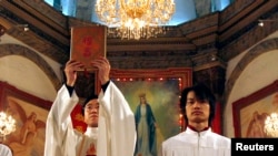 资料照: 北京天主教堂里的一名神职人员在做圣诞弥撒时高举中文版的圣经。(2007年12月24日)