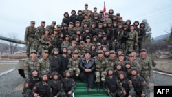 朝中社3月25日公布的照片显示,金正恩(中)3月24日与朝鲜人民军近卫汉城柳京守第105坦克师的士兵们一起拍照留念。