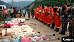 Lực lượng cứu hộ đứng trước thi thể nạn nhân thiệt mạng trong trận động đất ở huyện Lỗ Ðiền, tỉnh Vân Nam, ngày 4/8/2014.