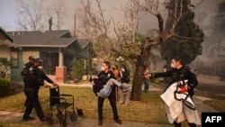 2025年1月8日,加利福尼亚州阿尔塔迪纳市伊顿大火期间,警察将一位老年人从家中疏散。