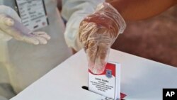 Seorang perempuan yang mengenakan sarung tangan plastik sebagai antisipasi wabah virus corona memberikan suaranya saat pemilihan kepala daerah di sebuah TPS di Tangerang, Rabu, 9 Desember 2020. (Foto: AP)