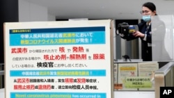 日本成田国际机场的工作人员在调整体温监测仪以测试从中国武汉和其他城市抵达的旅客健康状况。(2020年1月23日)