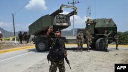 一名菲律宾士兵在参加美菲联合军演后在高机动多管火箭系统(HIMARS) 前用手机自拍。（2016年4月14日）