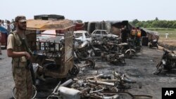 Một quân nhân Pakistan đứng canh trong khi nhân viên cứu trợ xem xét địa điểm một xe bồn chứa xăng nổ trên một xa lộ ở gần Bahawalpur, Pakistan ngày Chủ nhật 25/6/2017. Hơn 100 người thiệt mạng. (Ảnh AP/Iram Asim)