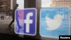 资料照:一家商店的橱窗上映照着推特和脸书的标识。