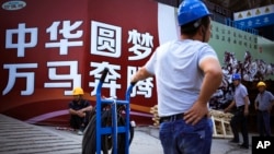 资料照：中国工人在北京一处建筑工地外展示的中国政府宣传“中国梦”的广告牌旁休息。（2016年9月5日）