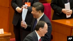 在北京人民大会堂举行的人民政治协商会议闭幕式上,中国国家主席习近平举着文件行走,和中共中央政治局常务委员王岐山擦身而过(2017年3月13日)。