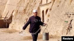 中国宁夏地区的一座棕色山丘上,村民走进一口井取水。(2003年2月17日)