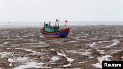 一艘渔船在越南清化省低潮期的海滩上(2018年6月4日)。