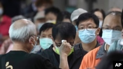 资料图片:2022年11月26日星期六,在台湾新北市一投票站,当地居民在投票前被检查体温。周六,台湾各地选民前往投票站参加备受关注的地方选举。在2024年总统选举之前,这次选举将决定台湾主要政党的实力。(美联社)