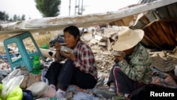 在北京郊区拆毁的建筑物废墟捡垃圾的两位民工吃午饭(2017年10月1日)