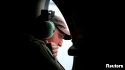 一架在印度洋南部上空搜索失踪马航班机残骸的澳大利亚皇家空军AP-3C猎户座飞机上的机组人员透过机窗查看海面。(2014年3月26日)