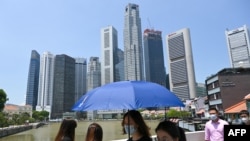 戴着口罩的人们走过新加坡金融区附近的一座桥。(2021年4月20日)