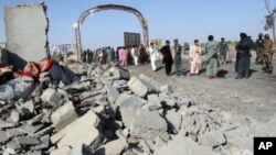 Afghan security forces and civilians walk at the site of a suicide attack in Lashkar Gah, capital of Helmand province, June 4, 2015.