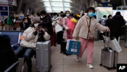 北京南站戴着口罩的旅客在候车室里等待。(2022年1月14日)