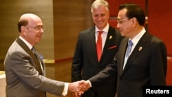 美国商务部长罗斯(左)与中国总理李克强在东盟峰会上握手,美国国家安全顾问罗伯特·奥布莱恩站立在两人身旁。(2019年11月4日)