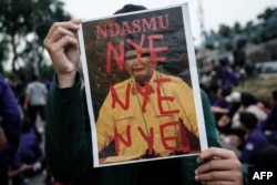 Seorang mahasiswa membawa poster bertuliskan "Ndasmu" dalam aksi protes menentang pemerintahan Presiden Prabowo Subianto, menuntut peninjauan ulang pemotongan anggaran pemerintah dan program makanan bergizi gratis di Patung Arjuna Wijaya, 20 Februari 2025. (Yasuyoshi Chiba/AFP)