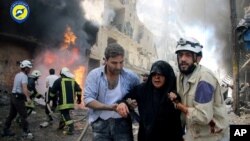 Lực lượng dân sự Syria giúp đỡ một người phụ nữ bị thương sau khi máy bay chiến đấu tấn công một con phố ở Aleppo, ngày 8/6/2016.