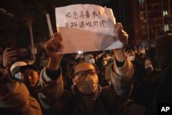 北京市民手举纪念乌鲁木齐11.24死难者的标语参加示威活动。(2022年11月27日)