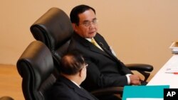 泰国总理巴育(上图)在议会特别会议上与副总理巴威交谈。(2020年10月26日)