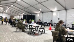 资料照片:在马里兰州一家由联邦紧急事务管理署和国民警卫队协助的大型新冠疫苗接种站,工作人员在等待接种民众前来登记。各地都在采取措施,鼓励民众接种疫苗。(2021年5月25日)