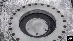 美国宇航局2023年10月11日提供的照片显示了奥西里斯-雷克斯样本收集器的外部,右边中间是来自小行星贝努的材料。(美国宇航局通过美联社发布)